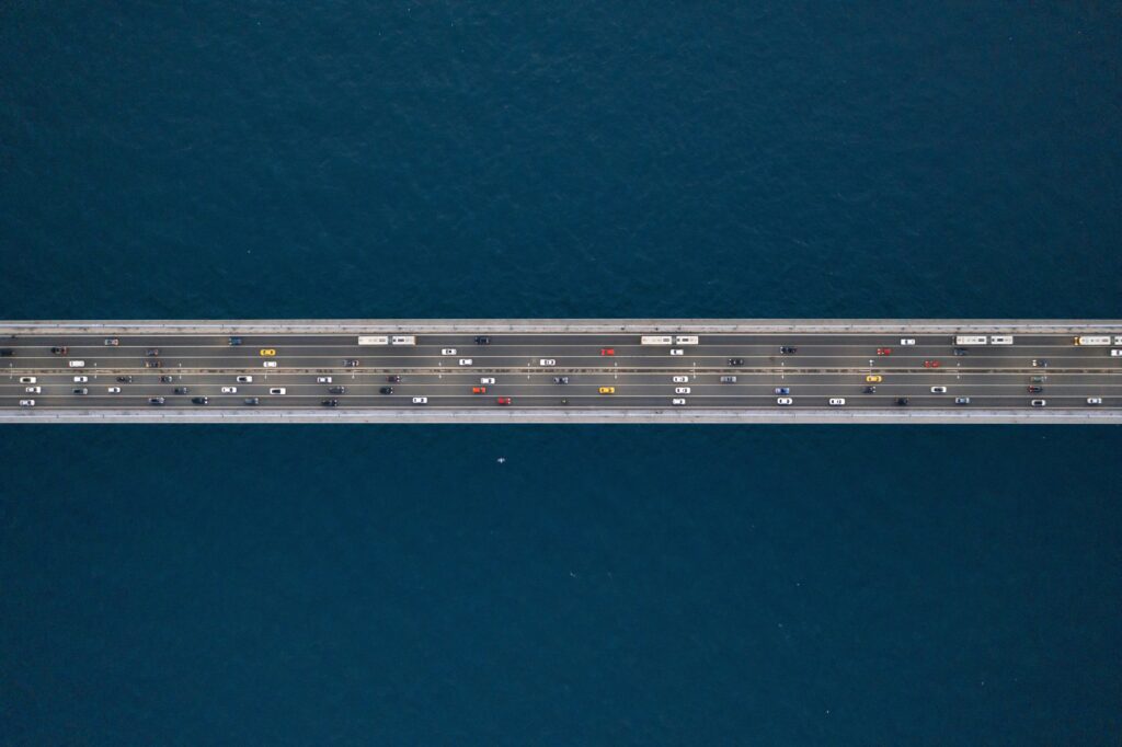 Aerial view of a multi-lane bridge carrying heavy traffic across deep blue water, symbolizing structured migration.