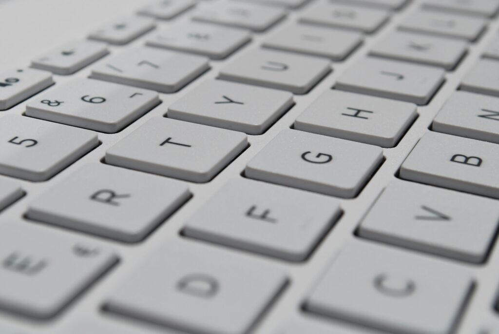Close-up of a white computer keyboard with letter and number keys, representing typing AI prompts for process design.