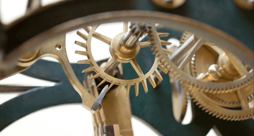 Close-up of interlocking brass gears and mechanical components in a clock mechanism, symbolizing business process systems.