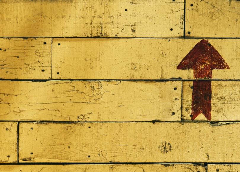 An arrow pointing up on a yellow wall.